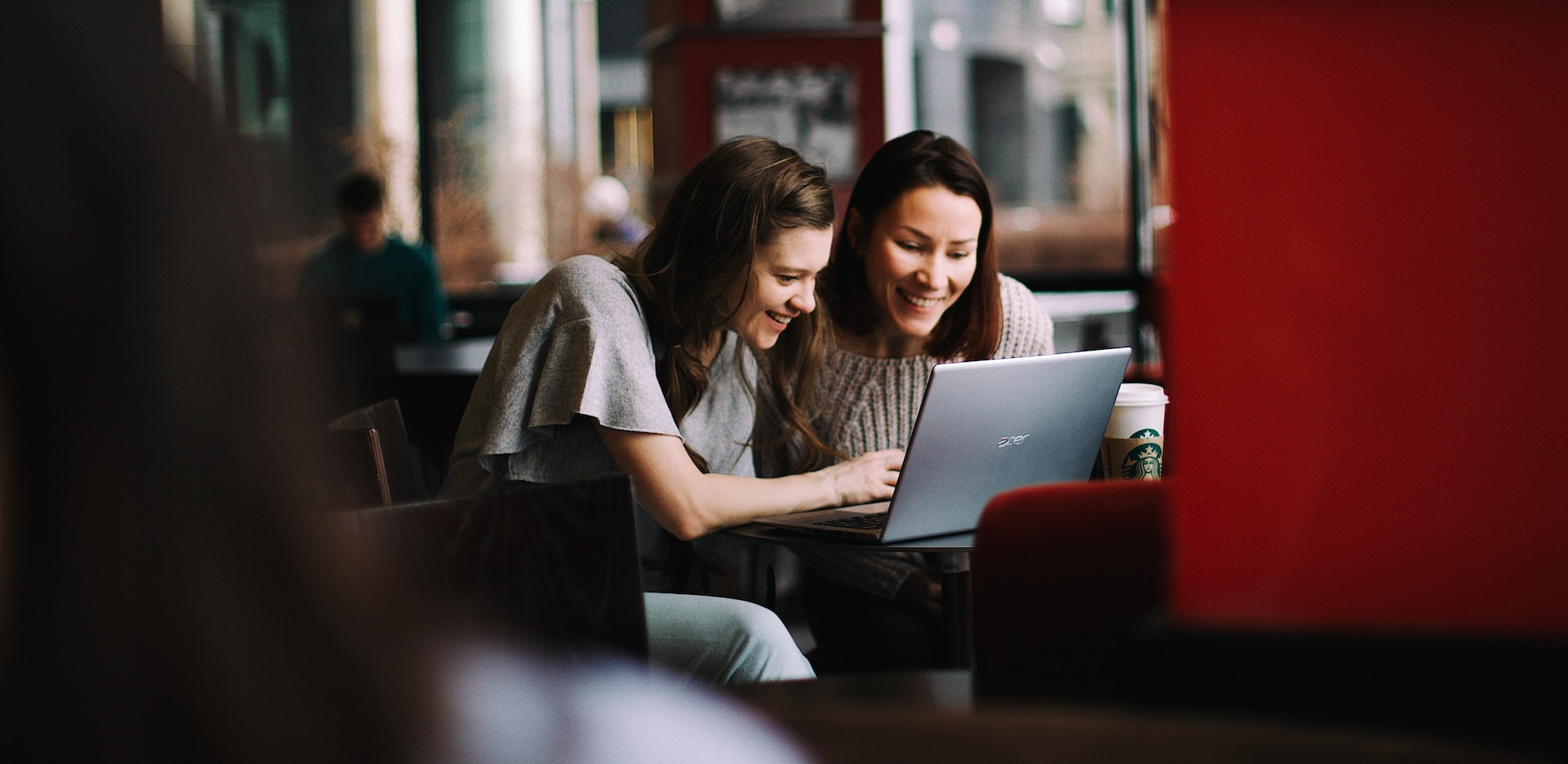 Duas mulheres em um café olhando o laptop atentamente e curiosas